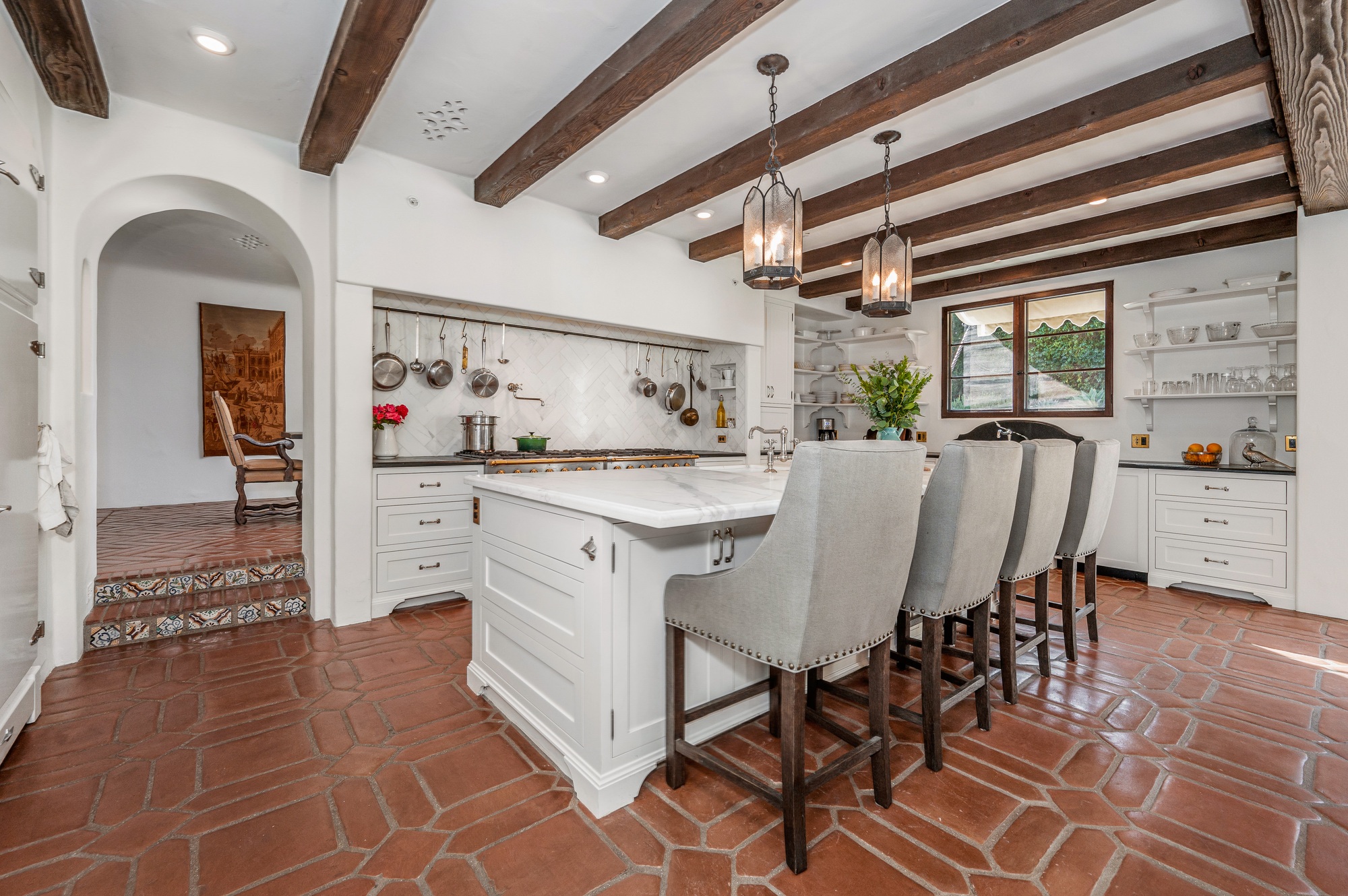 a kitchen with wooden beams and brown tile floors and flooring