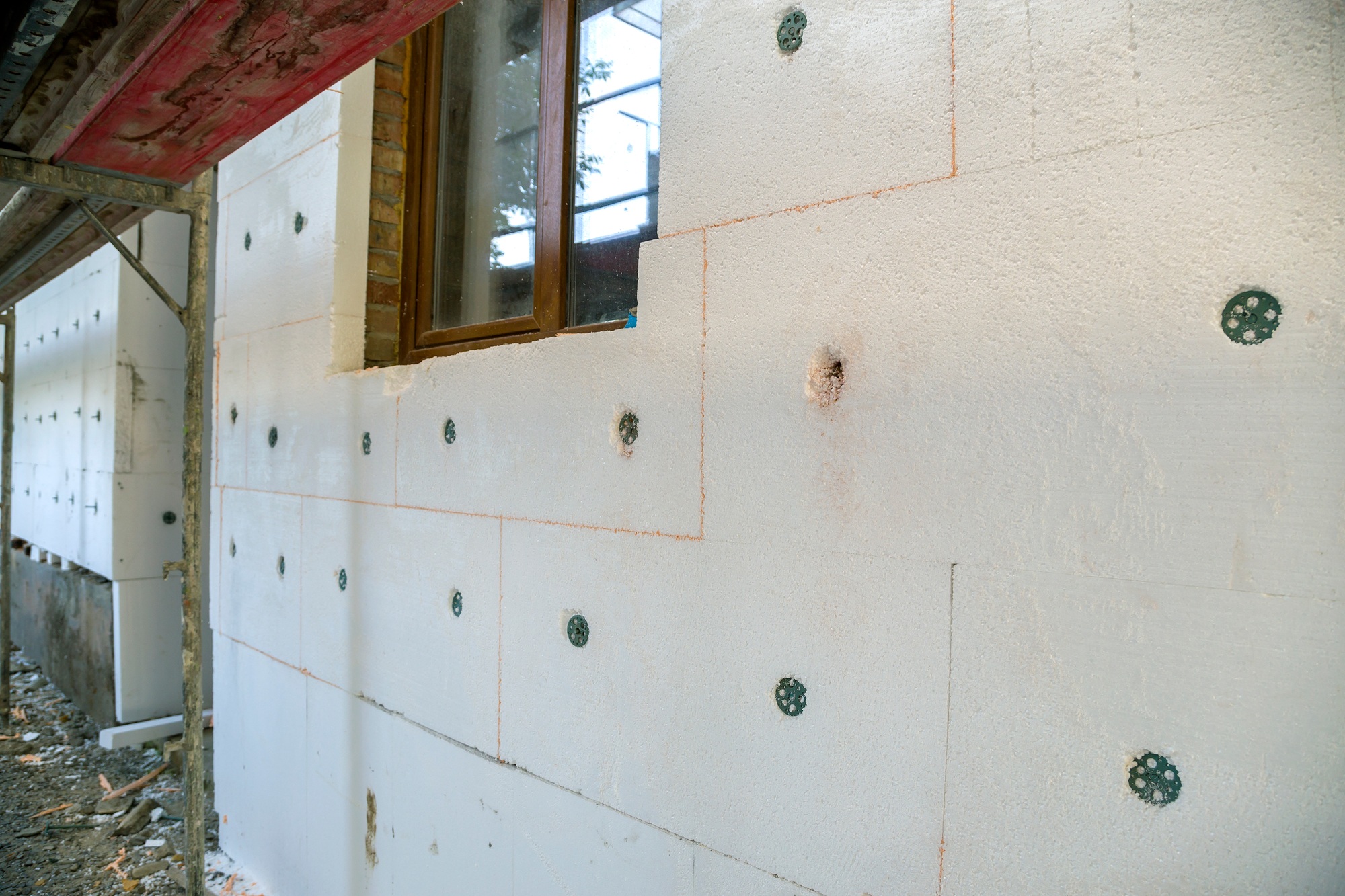 Insulation work of house walls with styrofoam sheets.